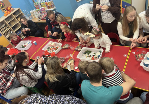 Rodzice z dziećmi wykonują kule śnieżne.