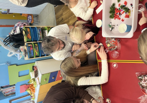 Dziewczynka z rodzicami robi kulę śnieżną.