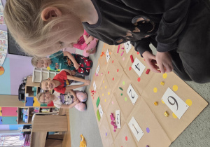 Dziewczynka układa 6 żółtych klocków na planszy.