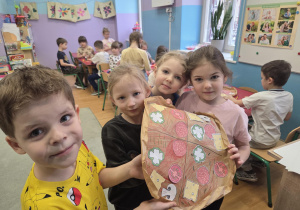 Czworo dzieci prezentuje wykonaną przez siebie pizzę.