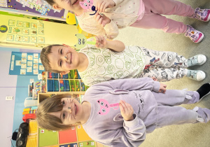 Troje dzieci trzyma w rękach wykonane przez siebie kotki.