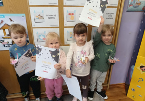 Dwie dziewczynki i dwóch chłopców prezentują dyplom i własnoręcznie zrobione koty z papieru.