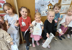 Dzieci uśmiechają się do zdjęcia, w rękach trzymając dyplomy pamiątkowe z okazji Dnia Kota.