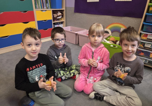 Dzieci ogrzewają w dłoniach lody z soku pomarańczowego, aby wydobyć je z pojemniczka.