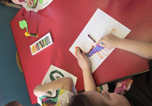 Dzieci rysują przy stoliku dinozaury.