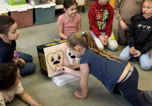 Dziewczynka segreguje obrazki na zdrowe i niezdrowe produkty dla zębów.