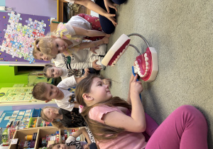 Dziewczynka prezentuje przy pomocy modelu szczęki, jak powinno się myć zęby.