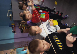 Dzieci za pomocą klamerek wieszają na sznurku filcowe części garderoby.