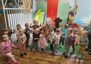 Grupa dzieci pozuje do zdjęcia z alpakami.