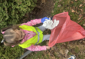 Dziewczynka wrzuca papier do różowego worka na śmieci.