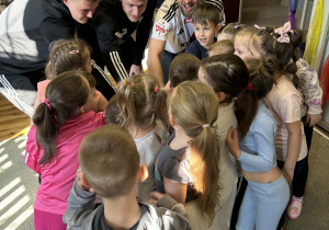 Dzieci wraz z piłkarzami szykują się do wspólnego okrzyku.