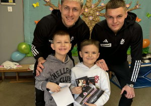 Dwóch chłopców pozuje do zdjęcia z piłkarzami ŁKSu.