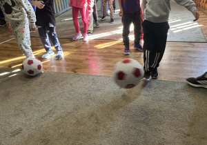 Dzieci kopią miękkie piłki do bramki.