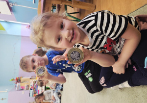 Dziewczynka i chłopiec trzymają w ręku papierowy symbol monety.