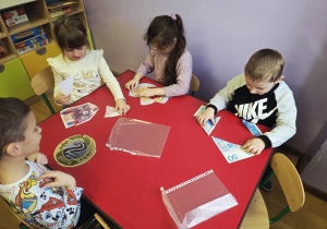 Dzieci siedzą przy stoliku i układają w całość puzzle z nominałami pieniędzy.