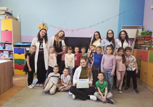 Grupa dzieci pozuje do zdjęcia ze studentami.