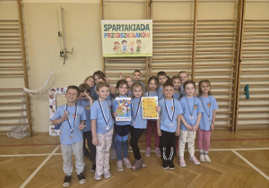 Grupa dzieci pozuje do zdjęcia z medalami i dyplomami.