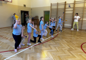 Dzieci rzucają woreczkami na przeciwną stronę sali gimnastycznej.